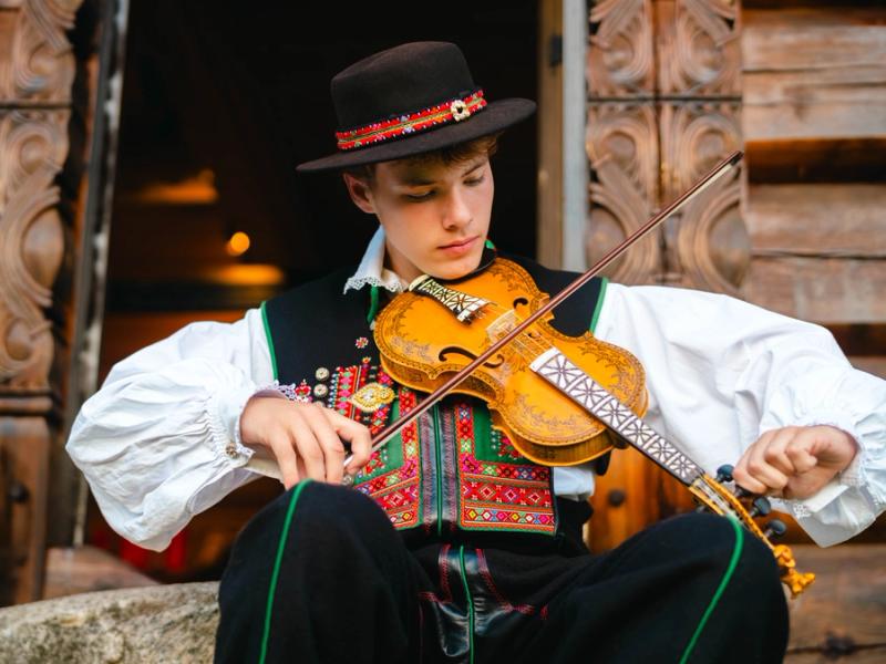 A young man from Setesdal playing the hardingfele (Hardanger fiddle), adorned with intricate decorations.