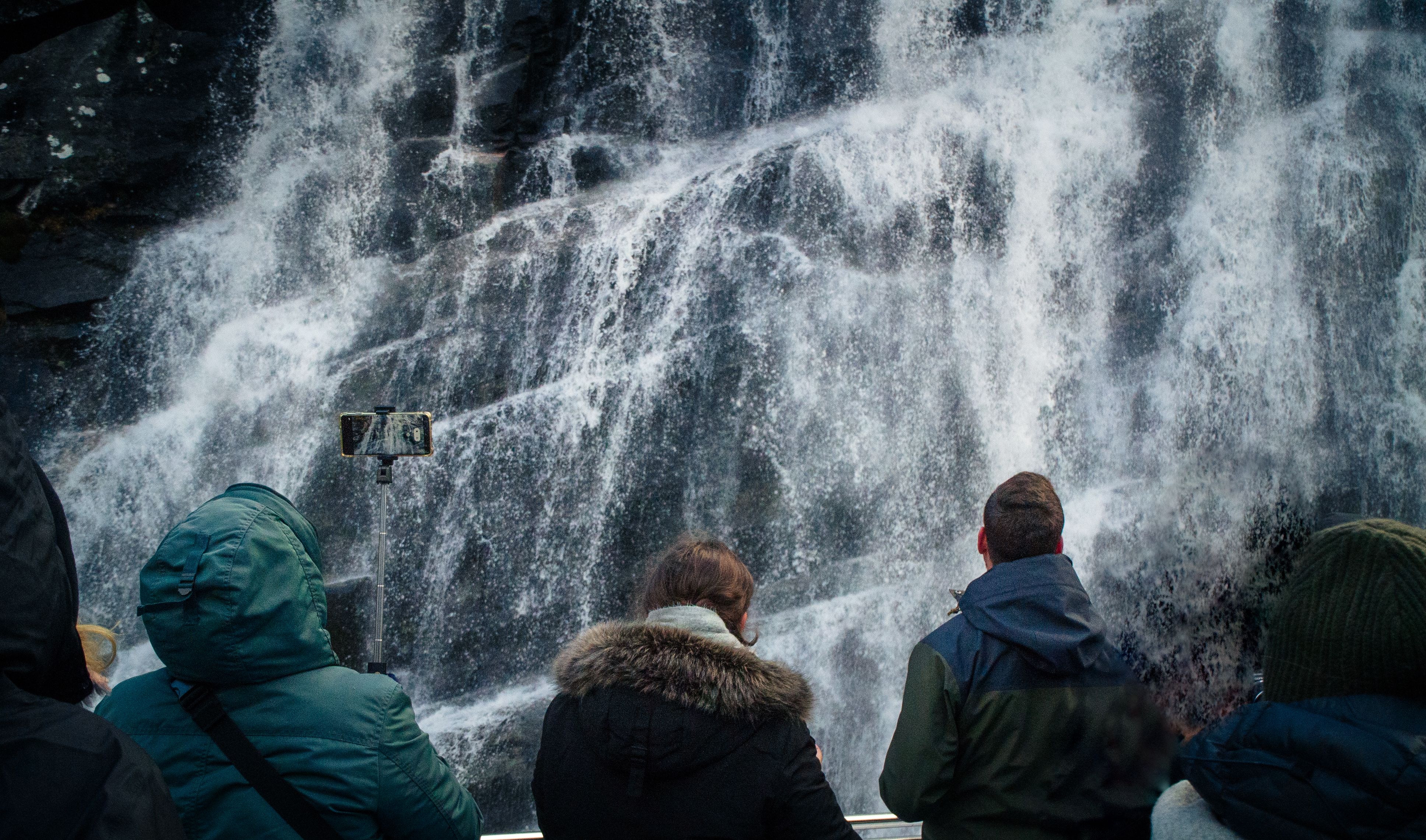 Passengers on a cruise boat getting a refreshing spray from the waterfall.