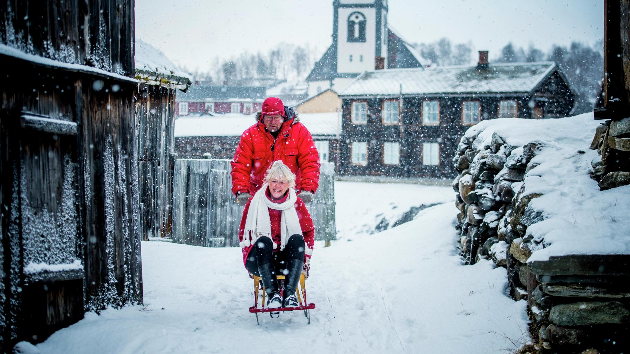 Two people on a kicksled in the snowy centre of Røros, Trøndelag, Norway