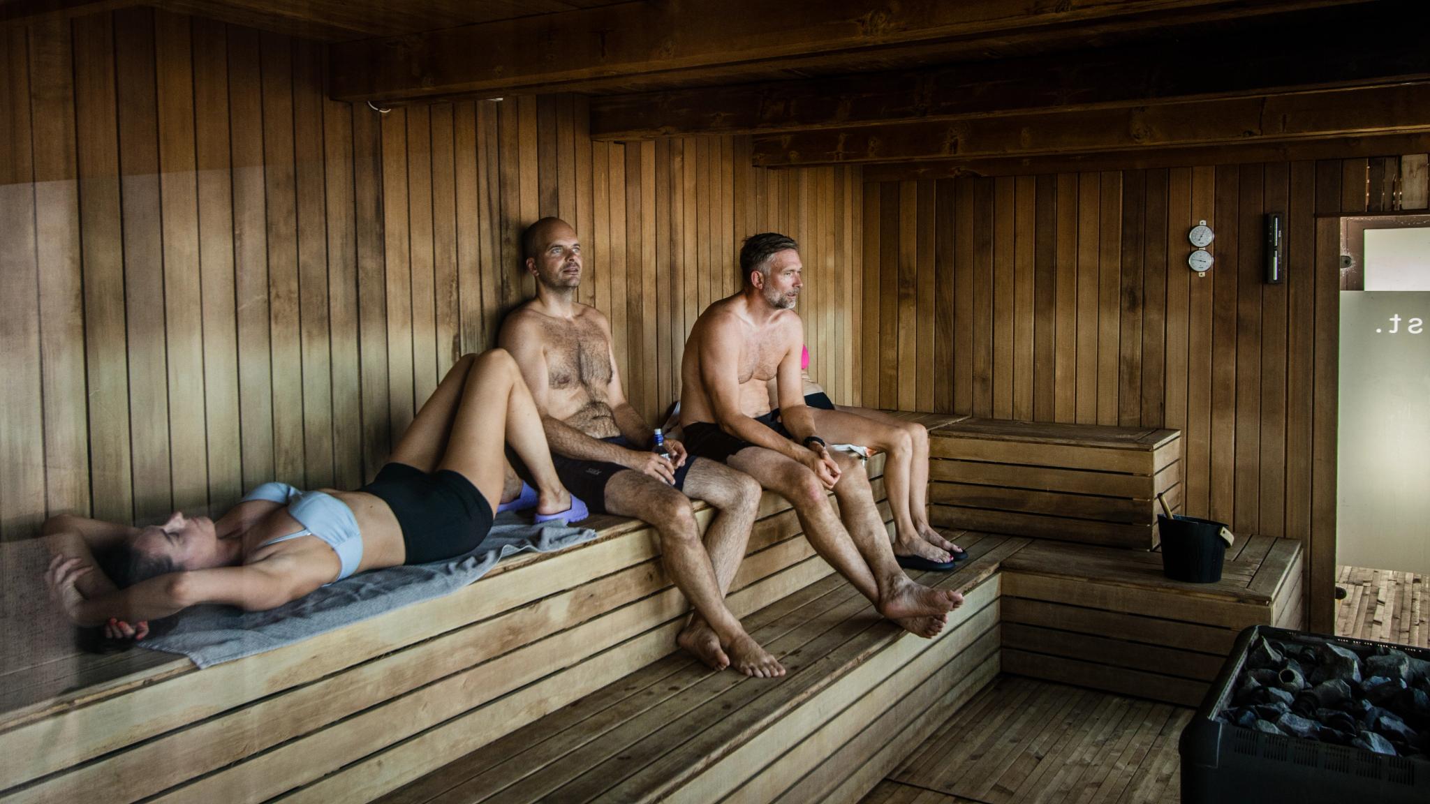 Three people sitting inside of the sauna Pust in Bodø.