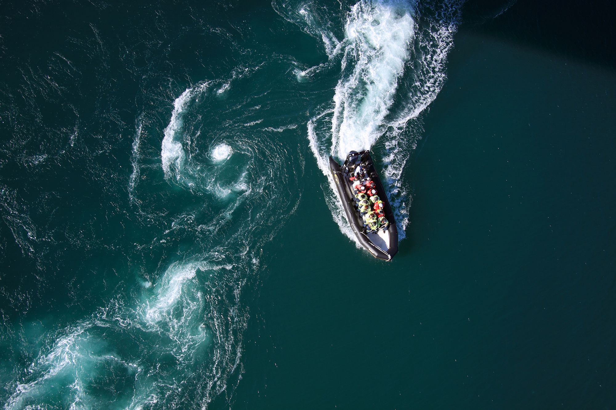 Un gommone con un gruppo di persone, visto dall’alto, percorre lo Saltstraumen a Bodø, Norvegia settentrionale