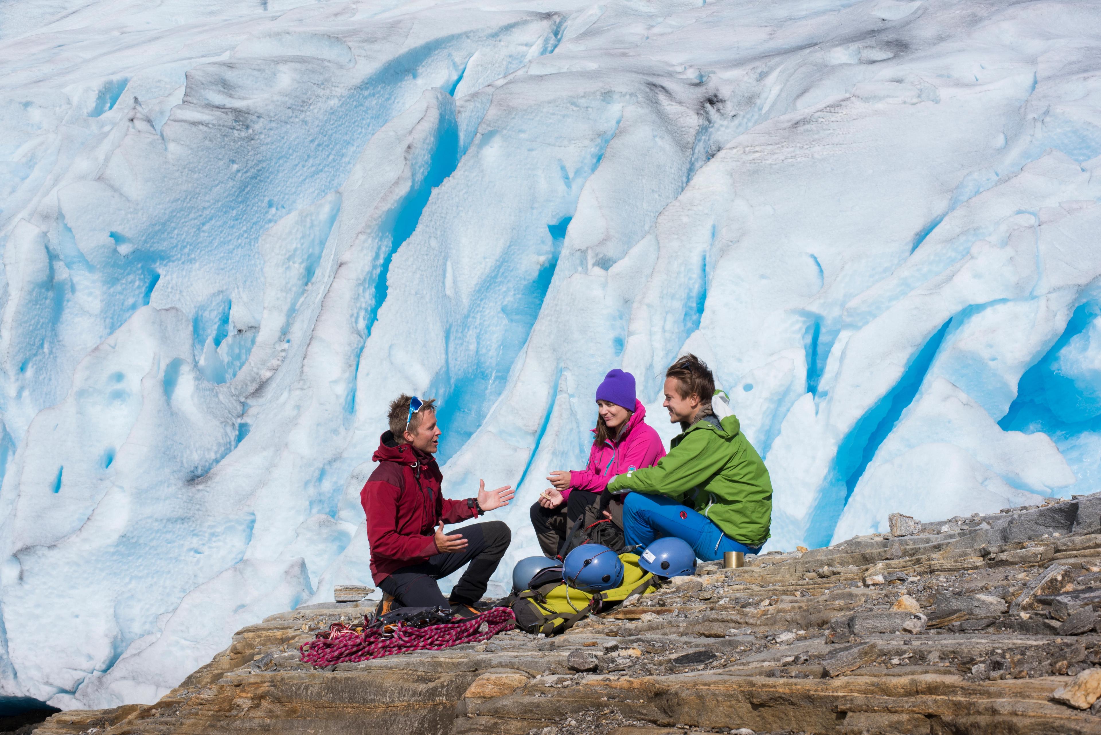 Three people sitting on a rock near the Svartisen glacier, Northern Norway