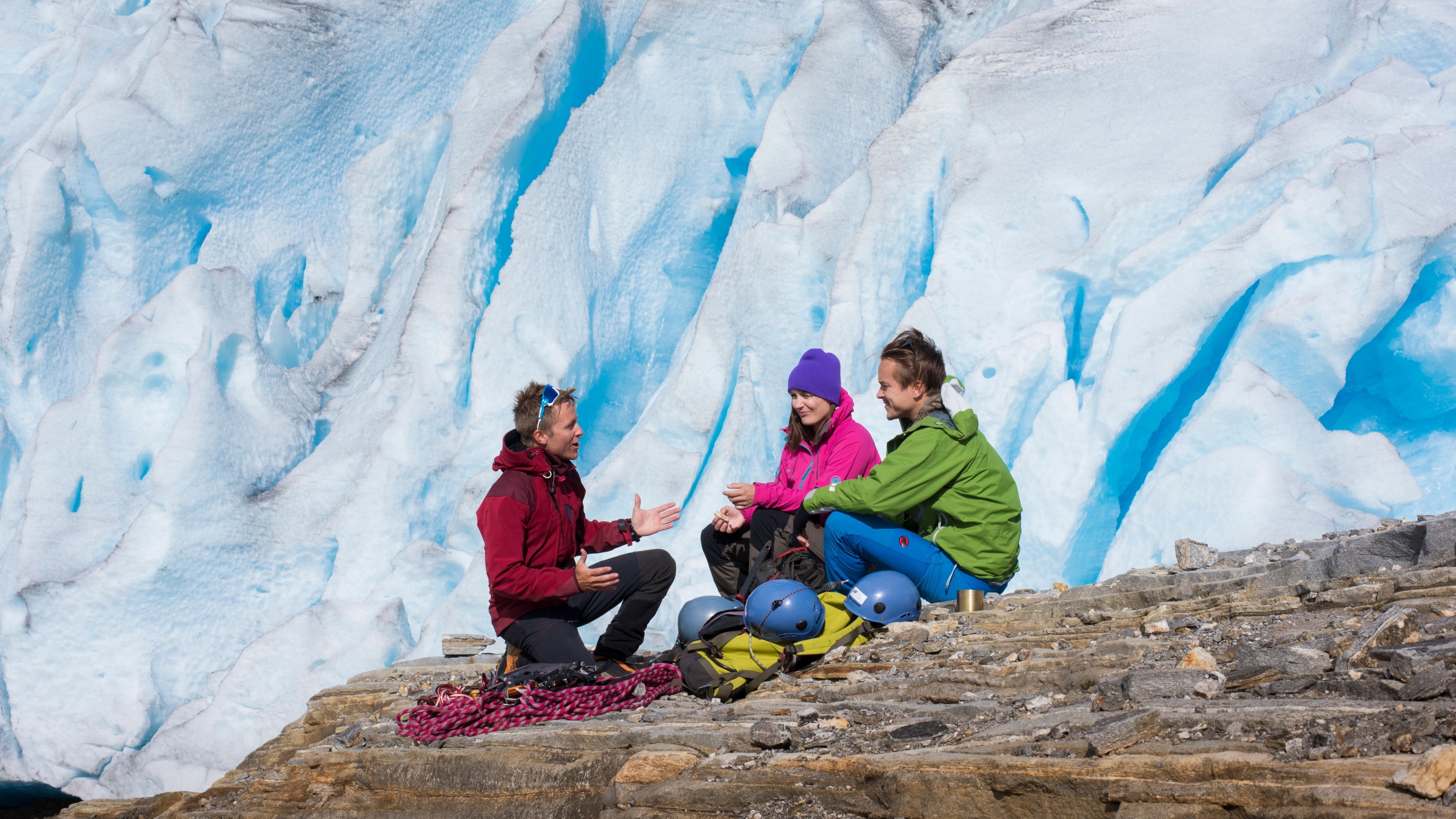Three people sitting on a rock near the Svartisen glacier, Northern Norway