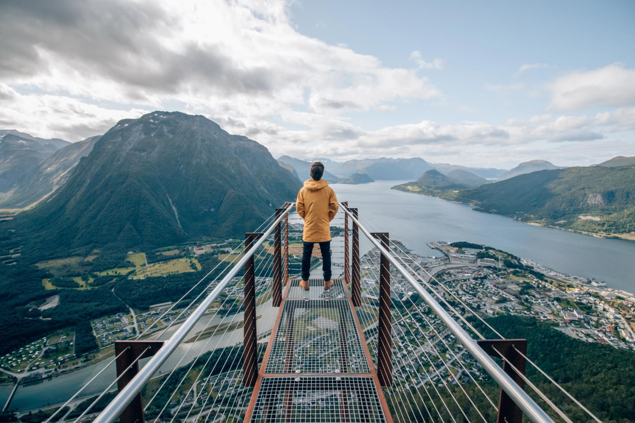 Una persona sulla punta della piattaforma panoramica Rampestreken osserva il fiordo e le montagne di Åndalsnes nel Nordovest dei fiordi, Norvegia dei fiordi