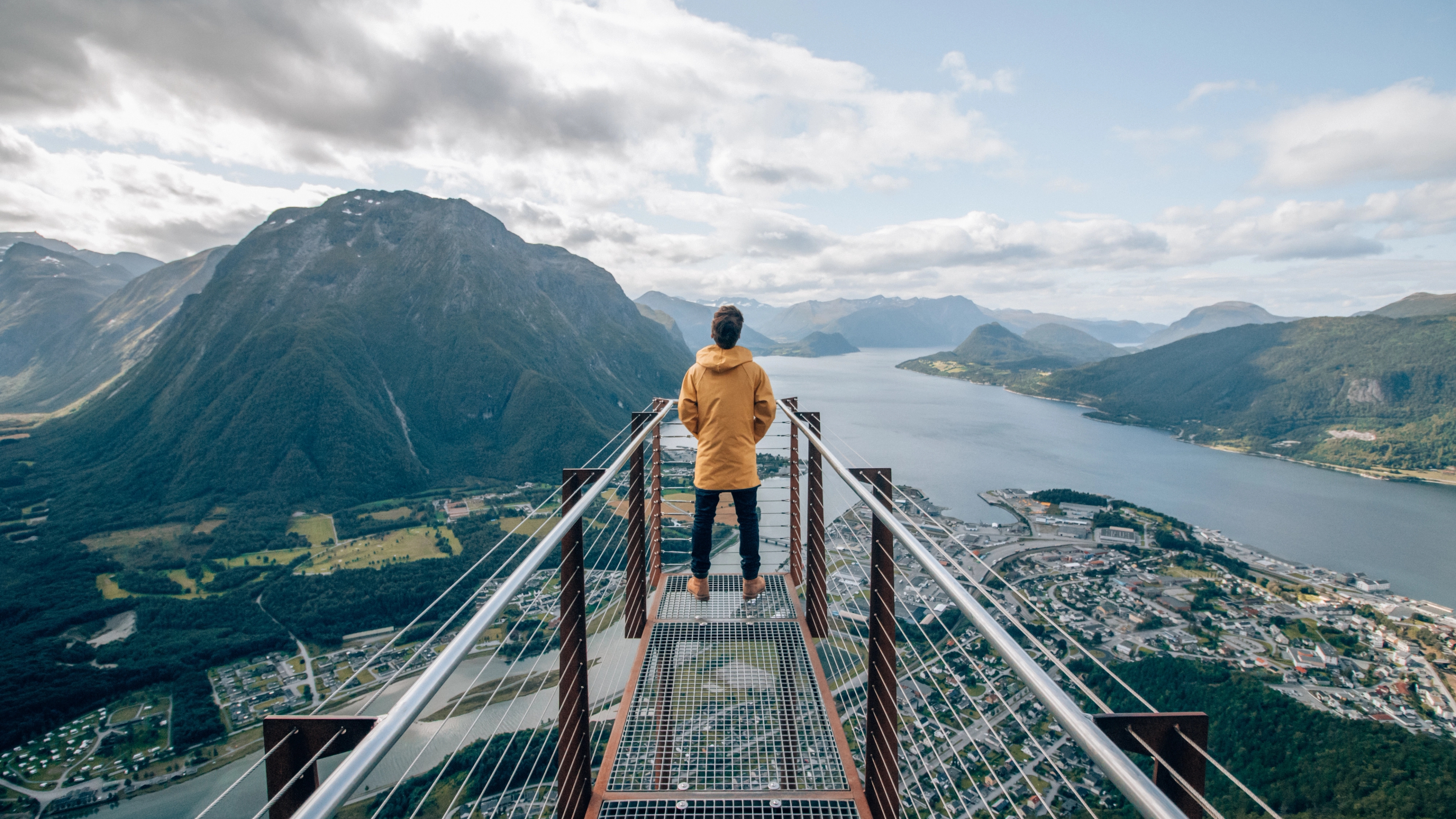 Eine Person an der Spitze des Aussichtspunkts Rampestreken schaut hinunter auf Berge, Fjorde und die Stadt Åndalsnes im Nordwesten Norwegens