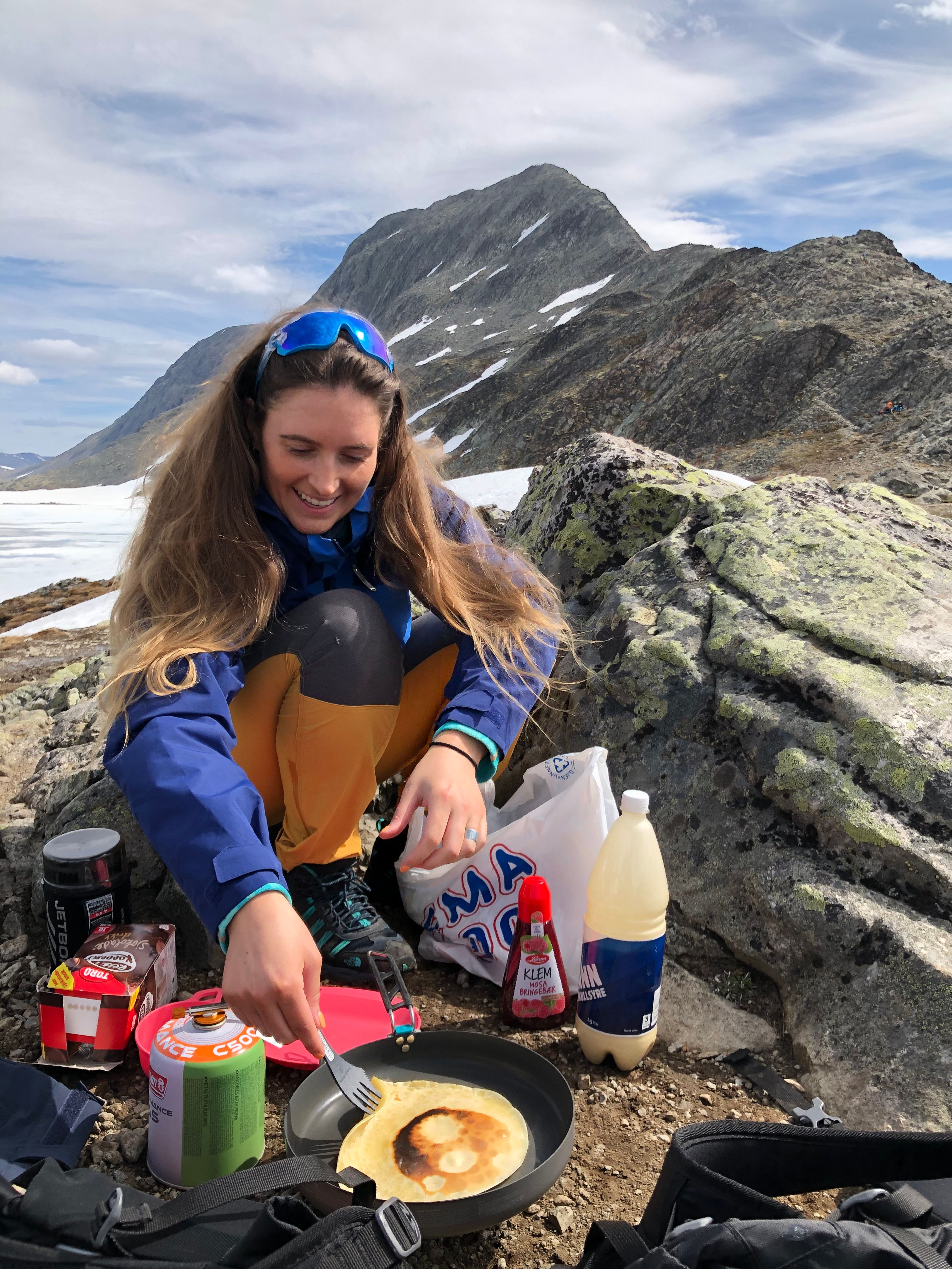 A woman making pancakes outside on the mountain