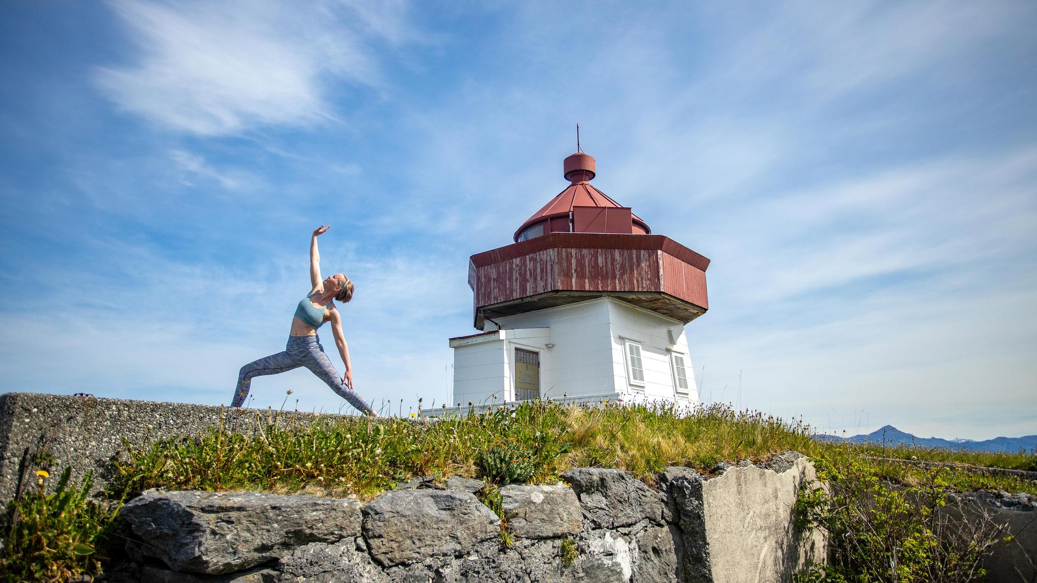 En dame, Rutt-Lovise gjør yoga, en "warrior" posering på Skongenes fyr