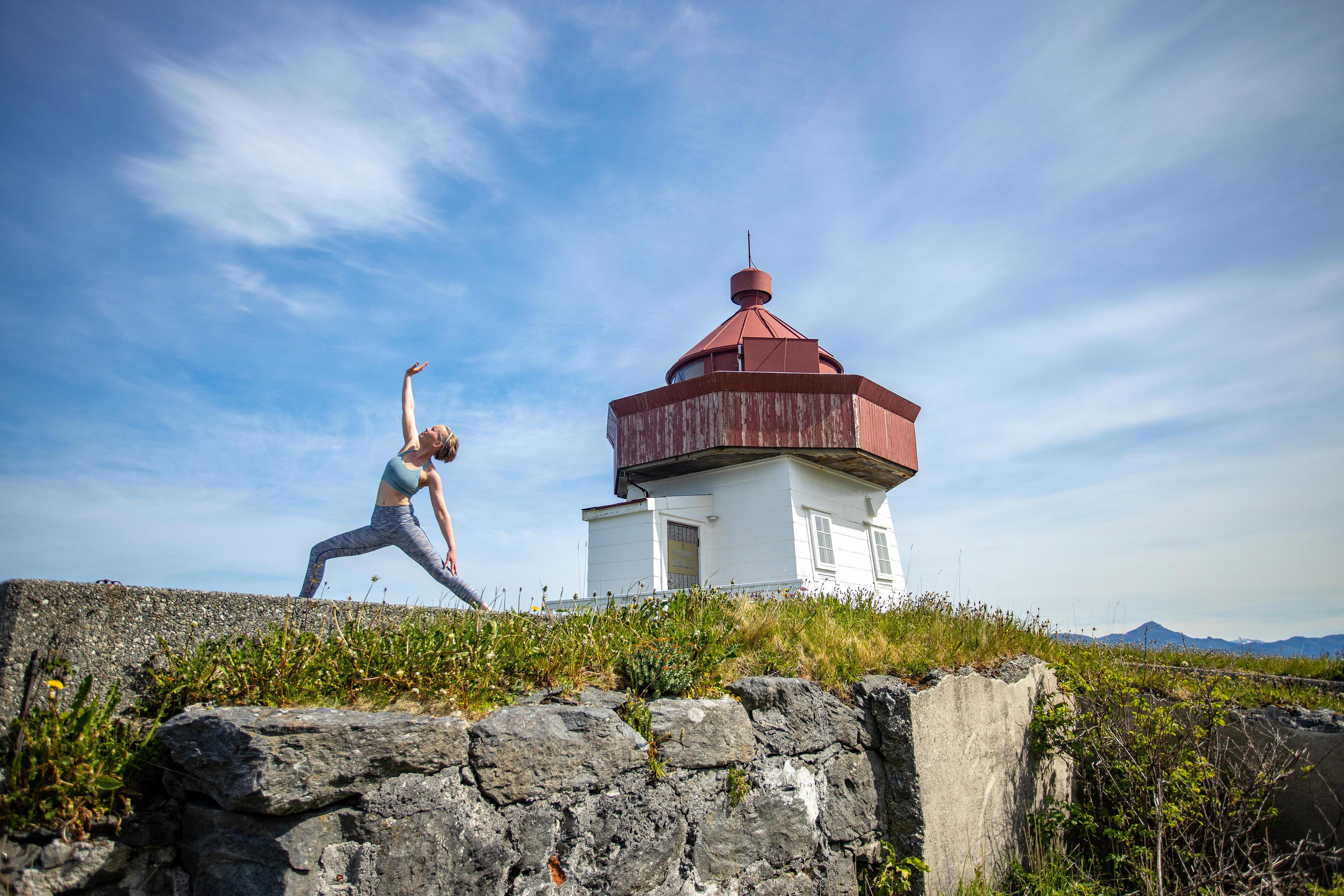 A woman, Rutt-Lovise are doing yoga, a warriors pose at Skongenes light house in Fjord Norway