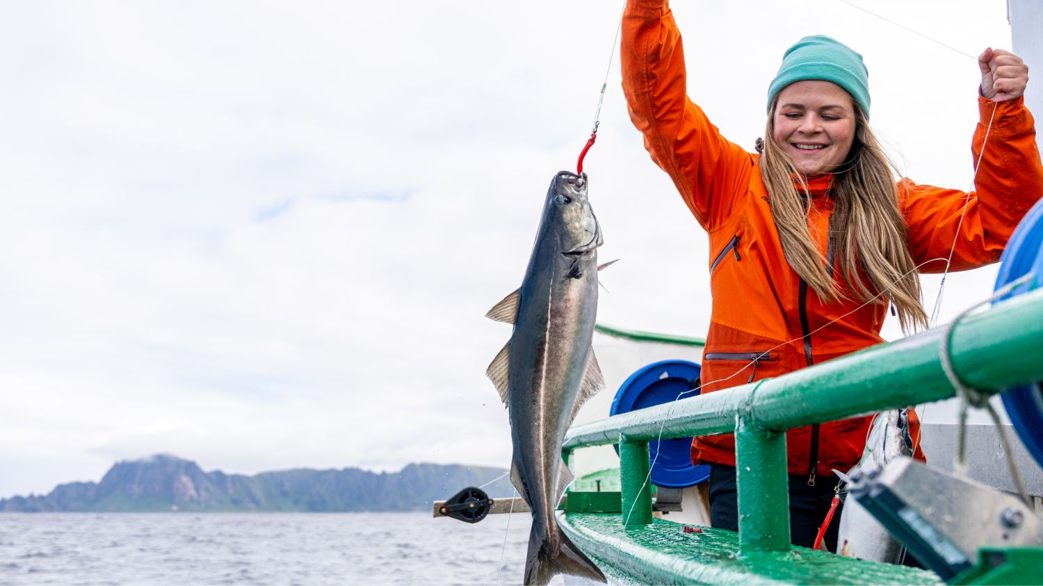 A lady pulling a fish on to a boat