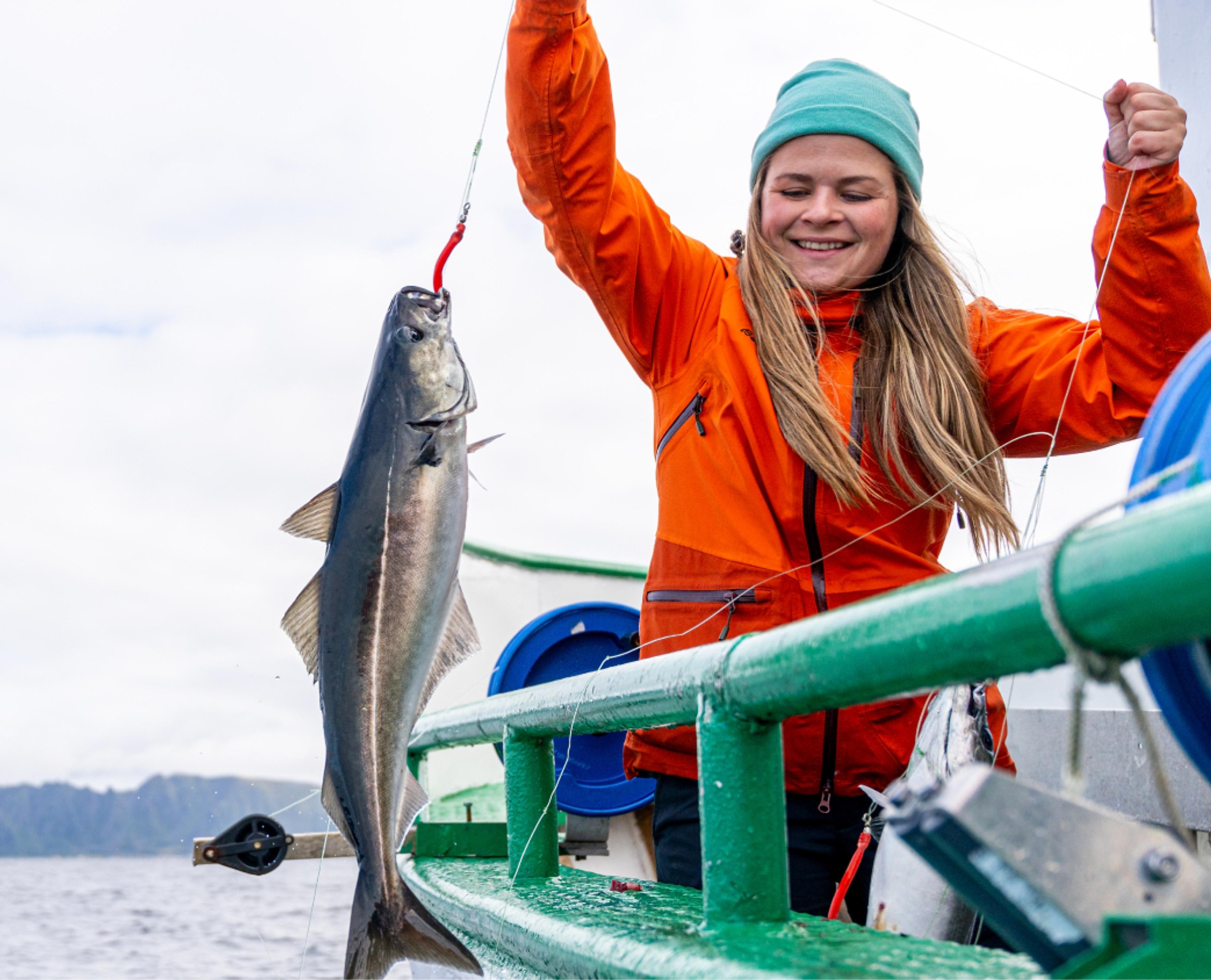 A lady pulling a fish on to a boat