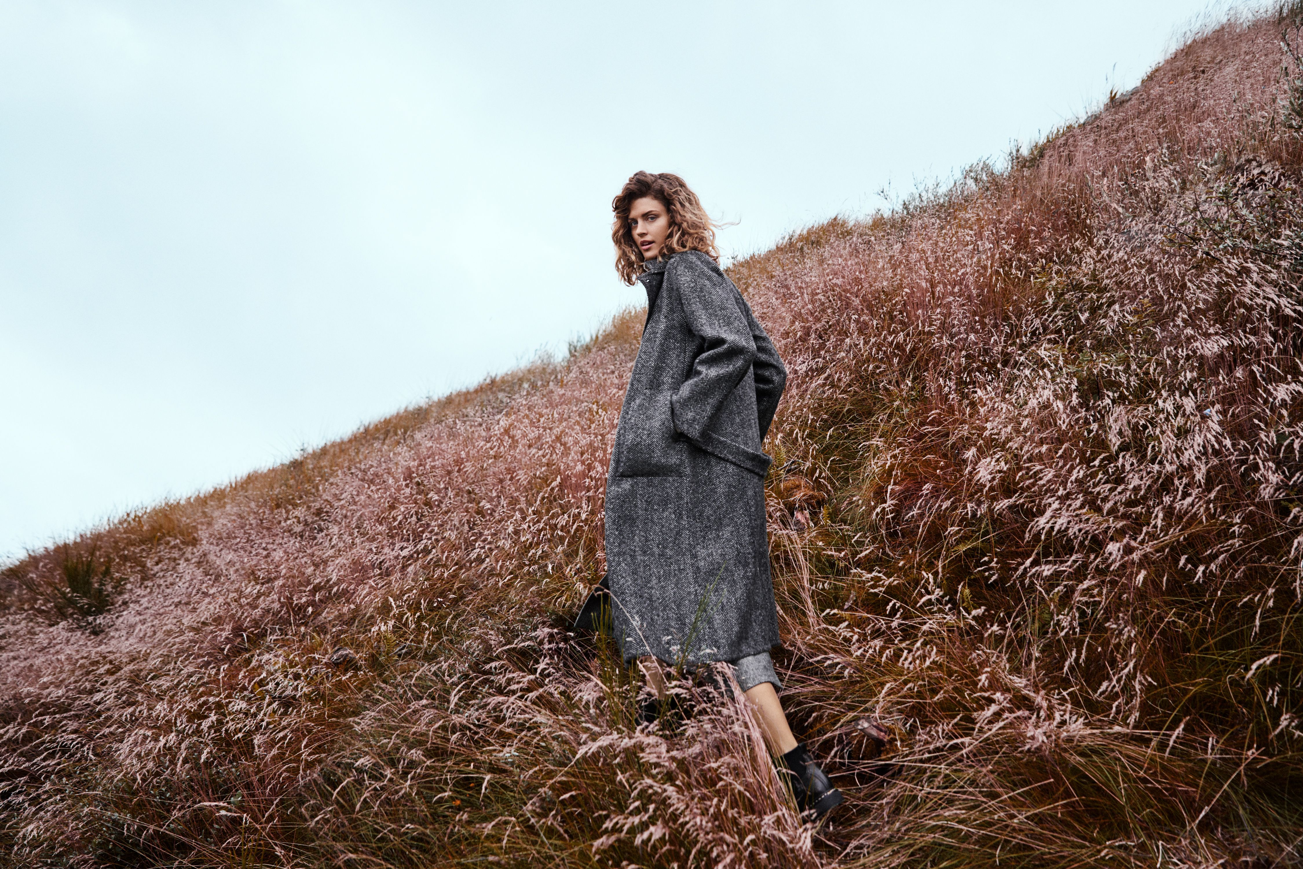 A girl in a grey woollen sweater in a meadow