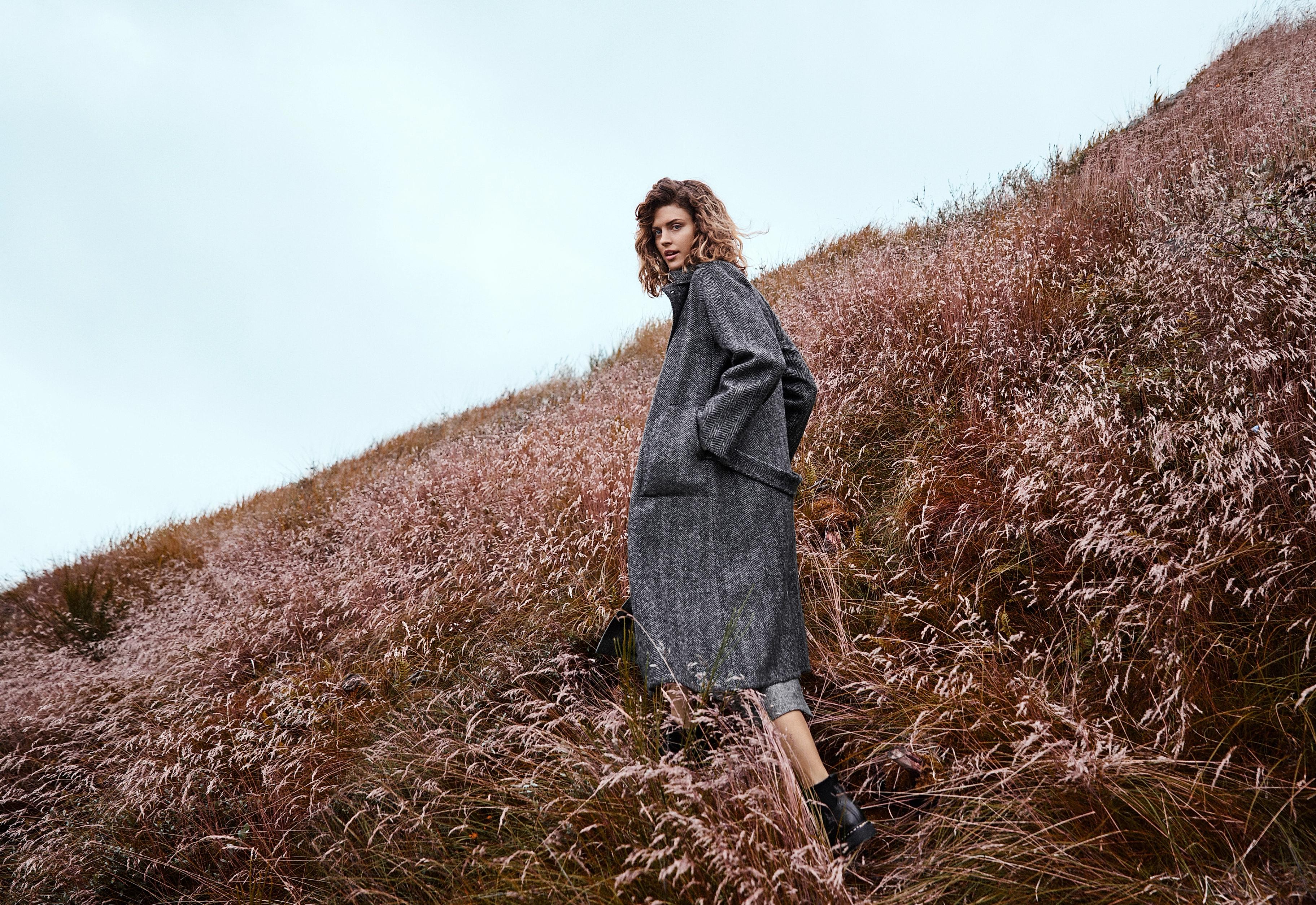 A girl in a grey woollen sweater in a meadow