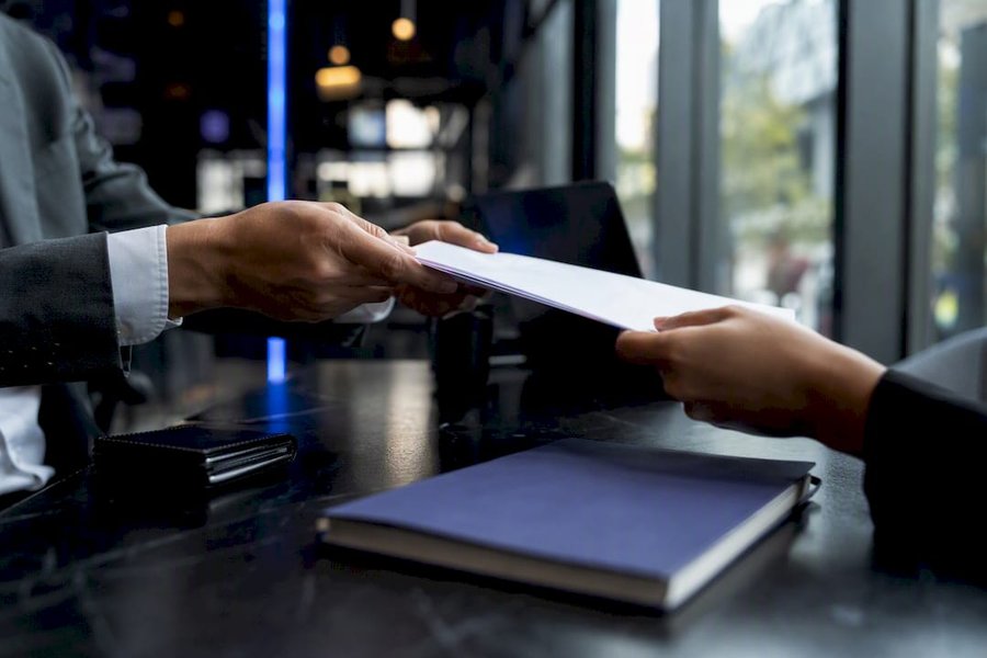 Hands exchanging contract with financial details blurred