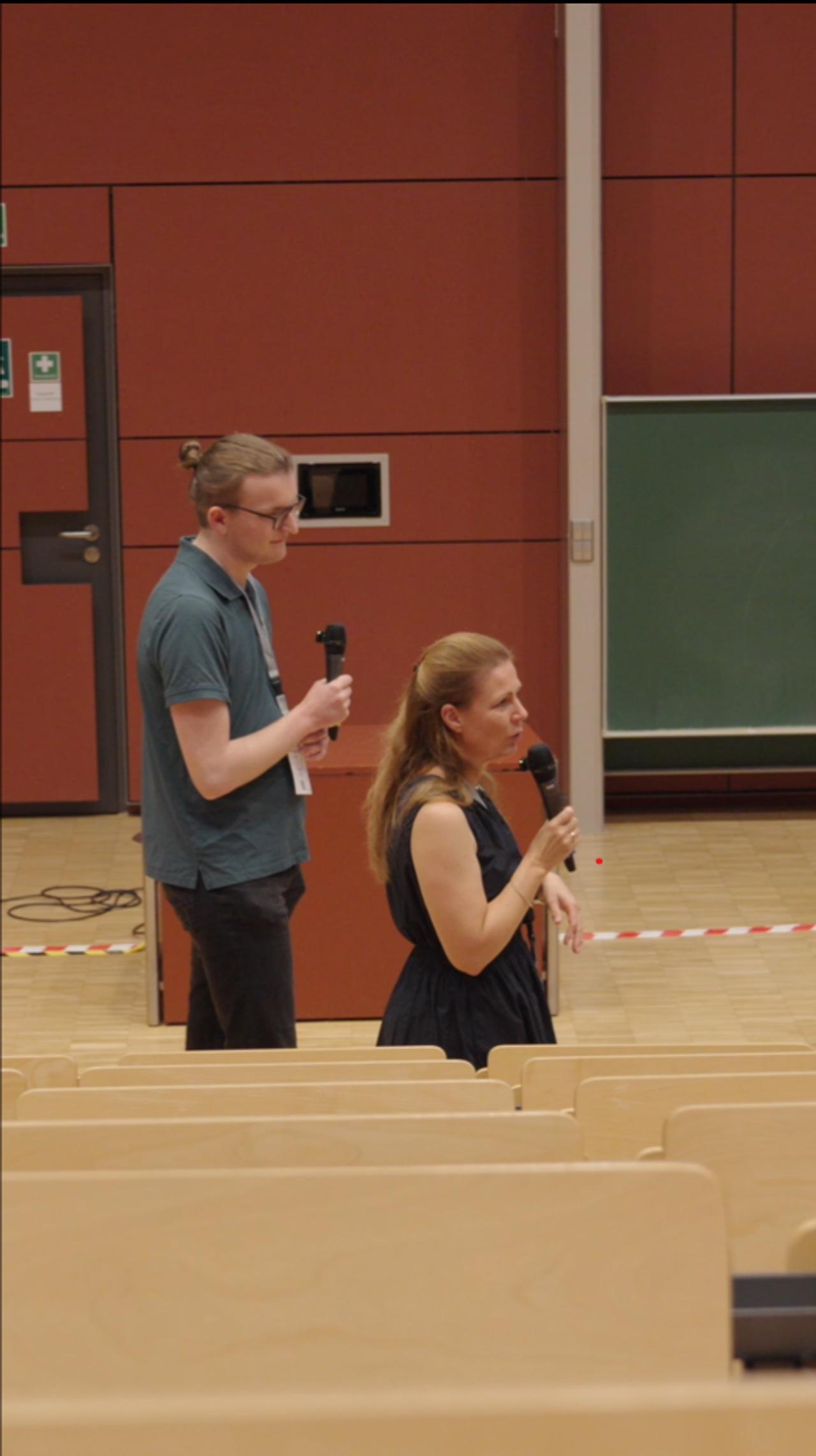 Vorschaubild: zwei Personen präsentieren in einem Hörsaal.