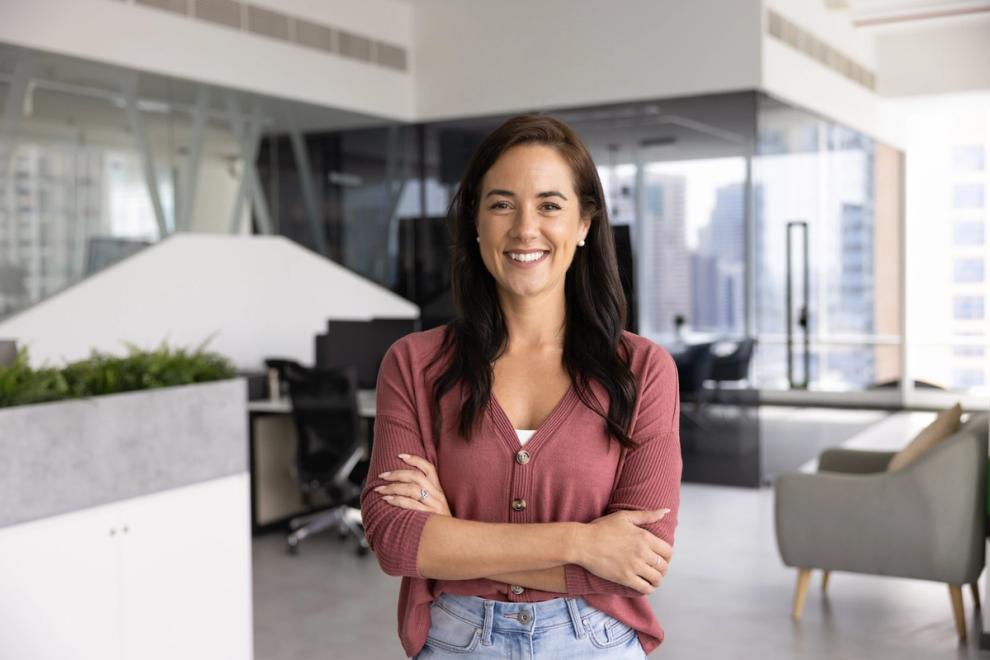 Smiling woman with arms crossed standing in a modern office