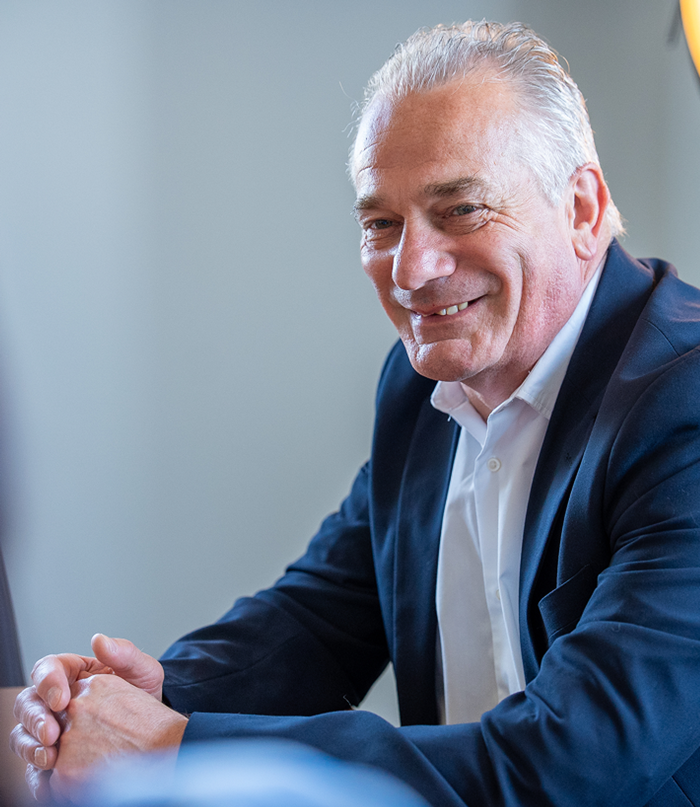 Simon Lawrence - man in dark blazer over light shirt, seated at desk
