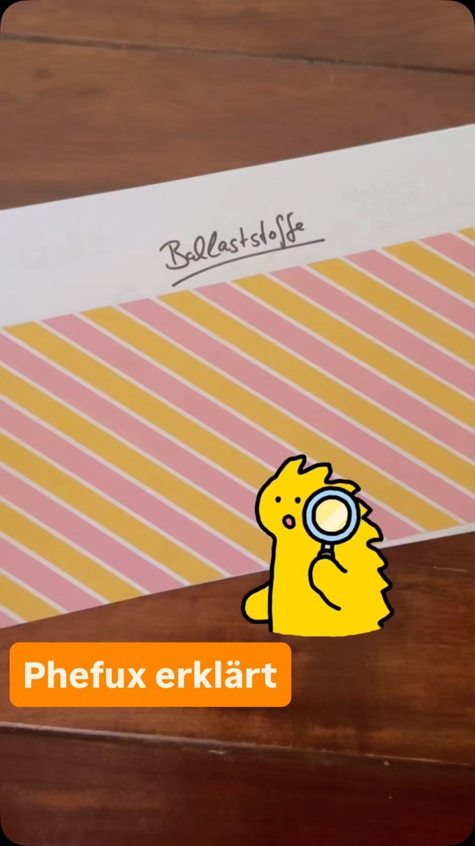 Phefux erklärt Ballaststoffe: gelbes Maskottchen mit Lupe auf gestreiftem Papier