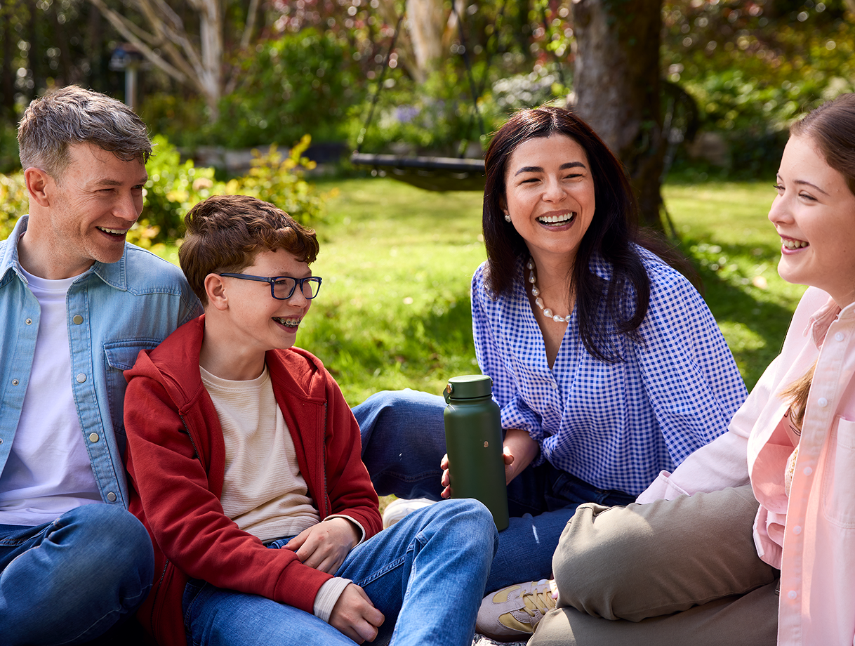 A family laughing together outdoors on a picnic blanket