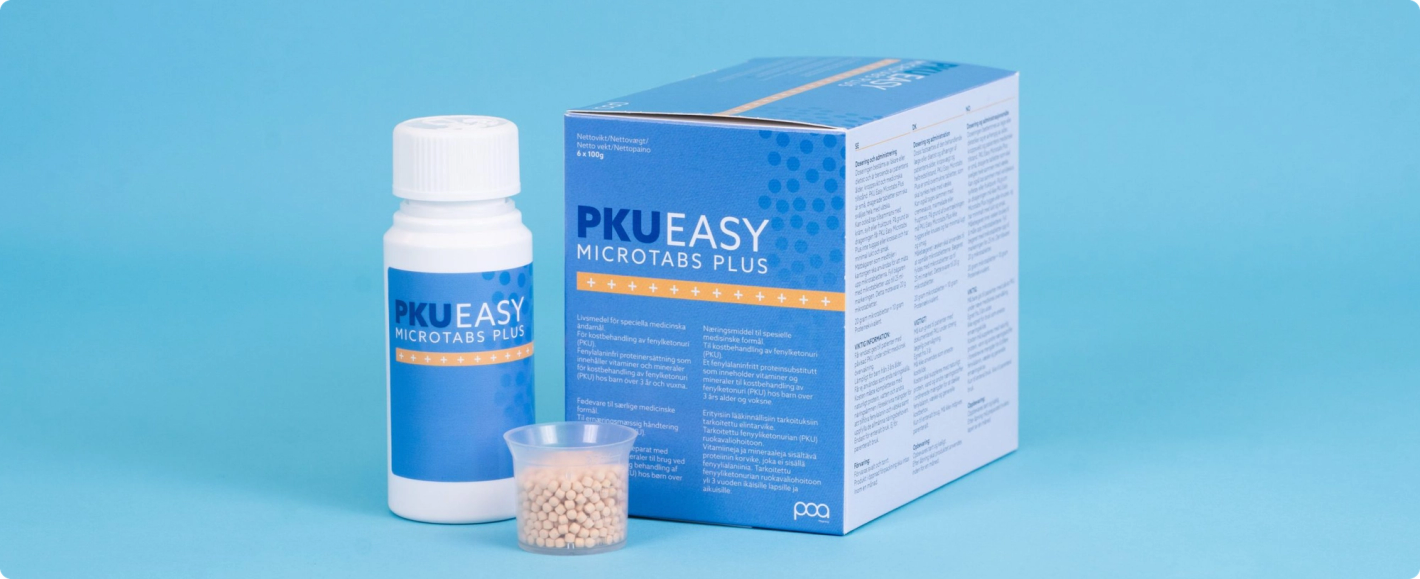 PKU Easy Microtabs Plus bottle and box displayed alongside a small cup of microtablets on a blue background
