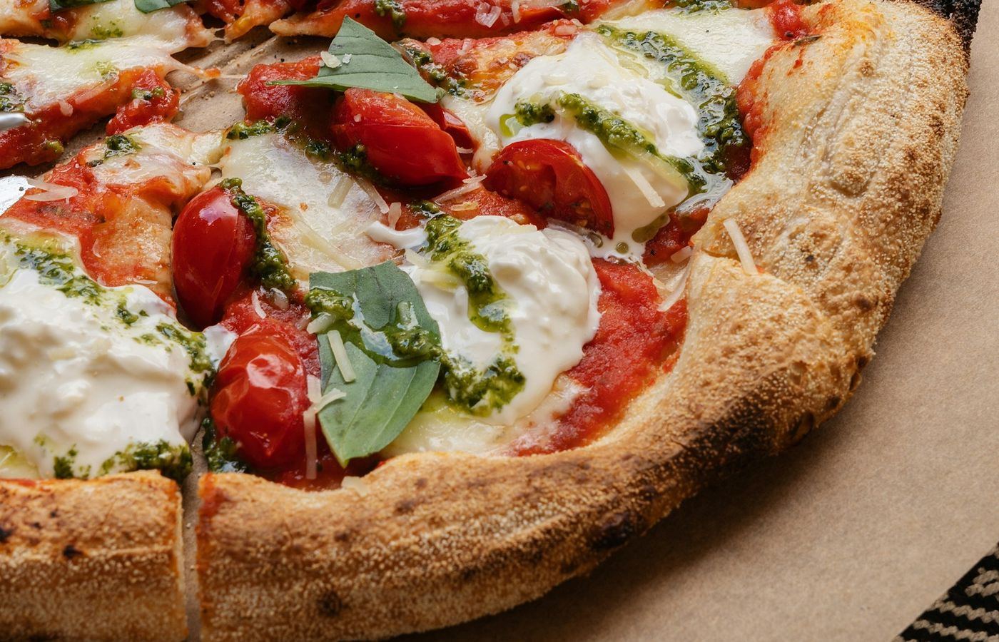 Pizza mit Burrata, Cherrytomaten, Pesto und frischem Basilikum