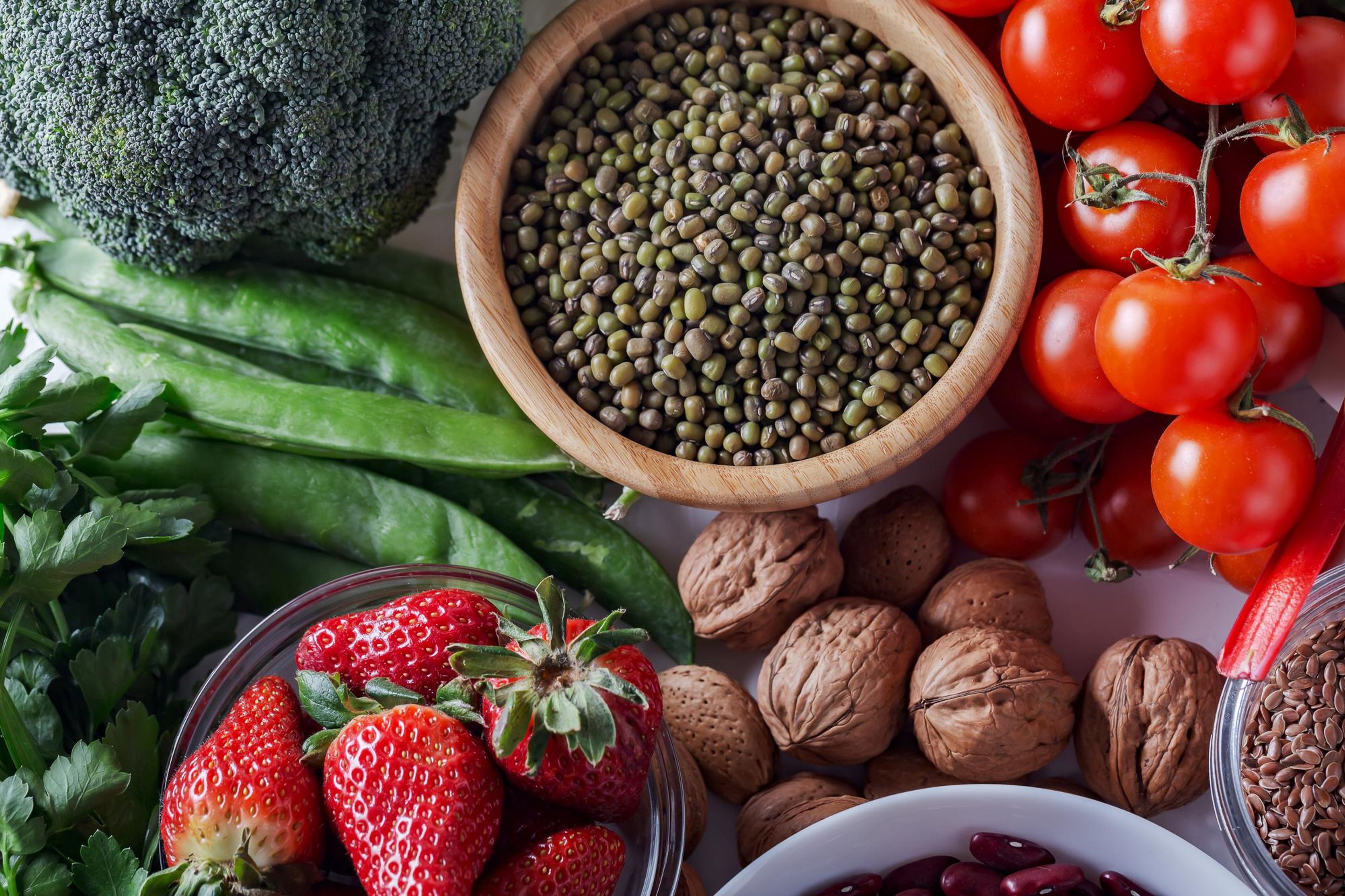 A vibrant collection of fresh broccoli, peas, strawberries, mung beans, tomatoes, and walnuts.