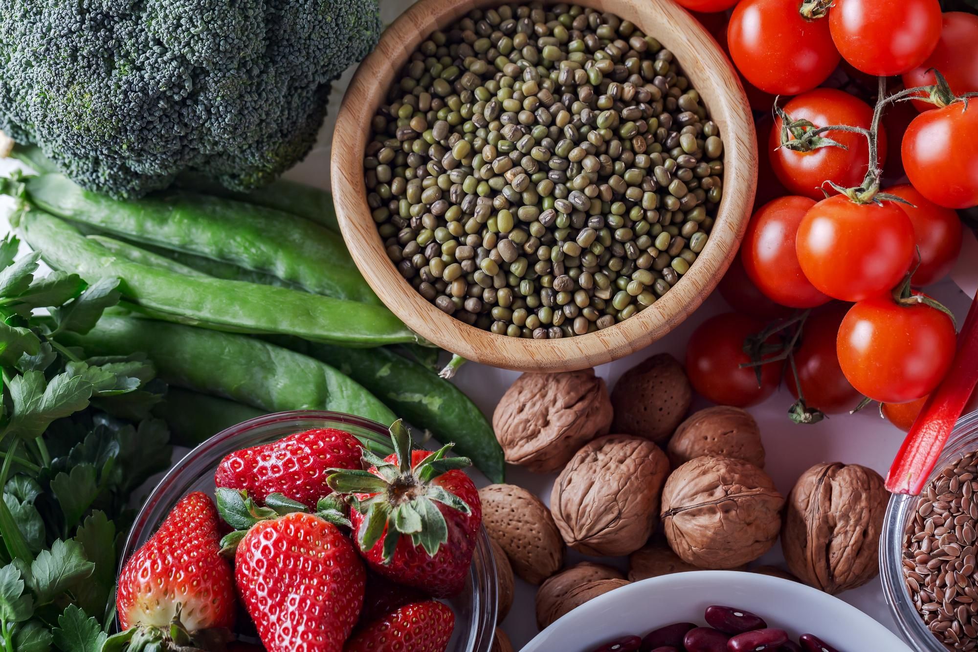 A vibrant collection of fresh broccoli, peas, strawberries, mung beans, tomatoes, and walnuts.