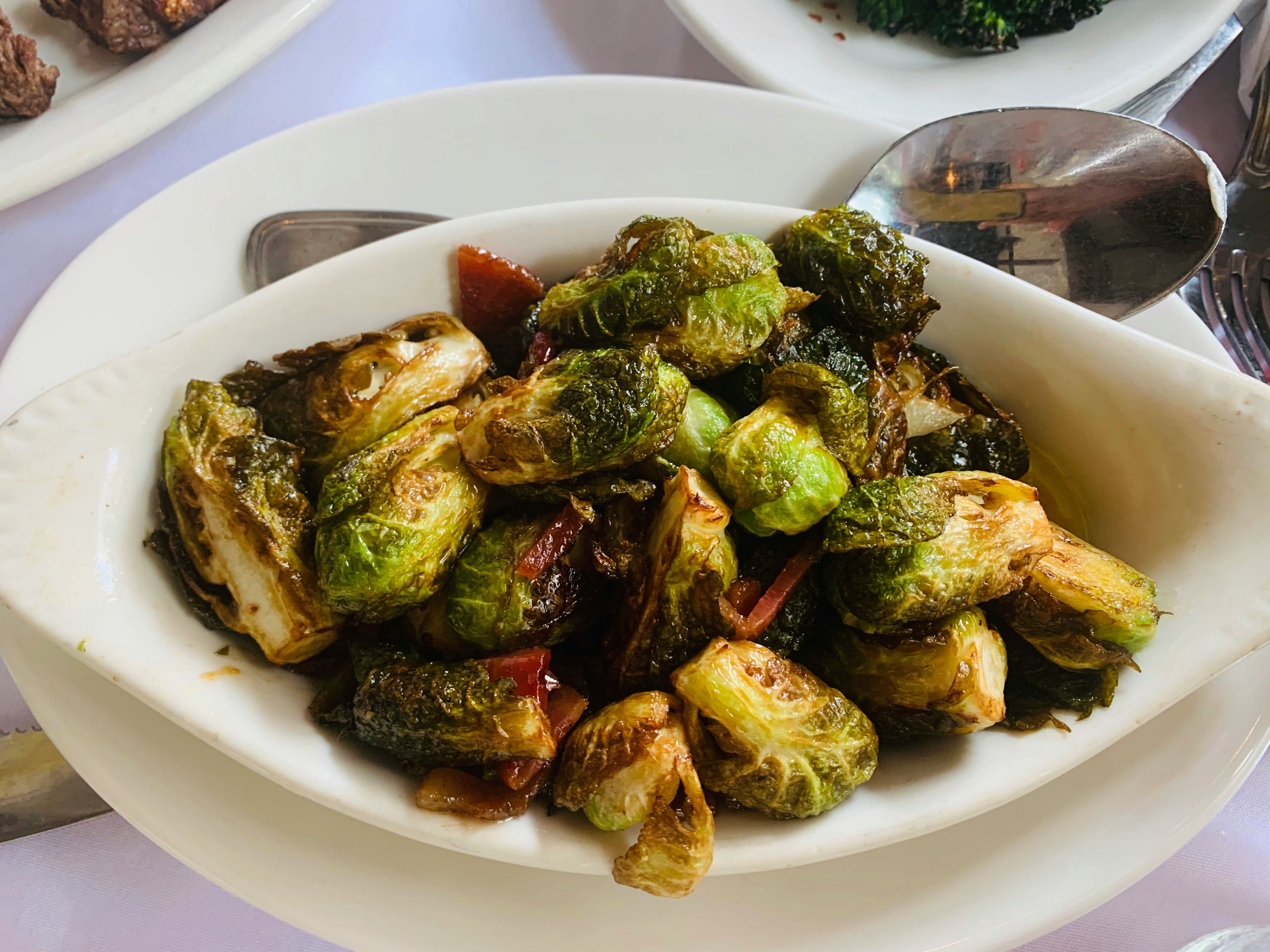 A white serving dish filled with roasted Brussels sprouts.