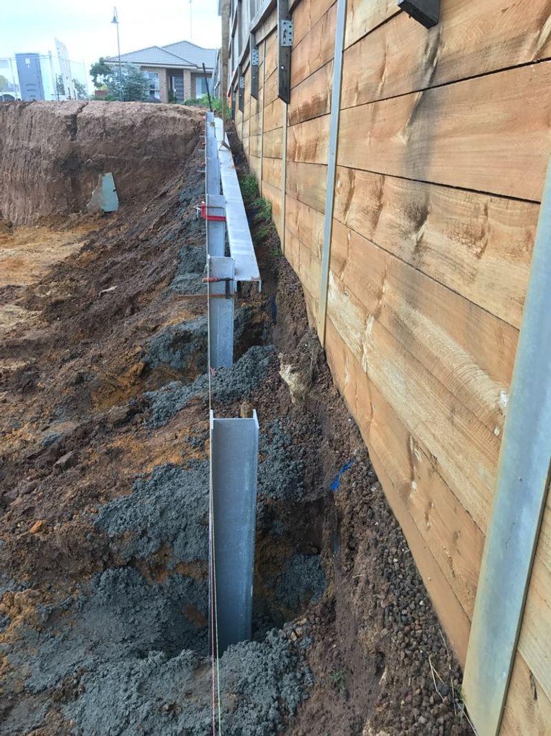 Galvanised steel retaining wall posts concreted into staged excavation bays