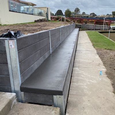 Concrete sleeper retaining wall with poured concrete bench seating beside the green at Belmont Bowling Club, Geelong