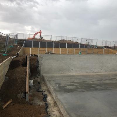 Bulk excavation and multi-level retaining walls — timber sleepers, concrete walls and dark sleeper terraces on a sloping estate site