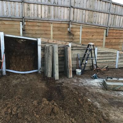 Timber sleepers being installed between steel posts during a staged boundary retaining wall build in Geelong
