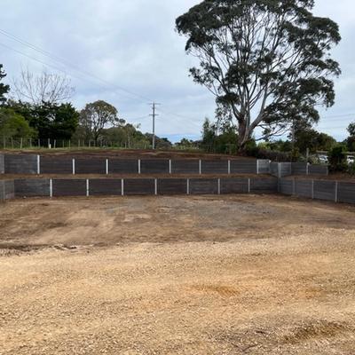 Large terraced dark sleeper retaining walls wrapping a levelled gravel hardstand area on the Bellarine Peninsula