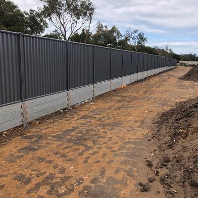 Long run of Colorbond fencing built on a concrete sleeper plinth retaining wall along a new estate boundary