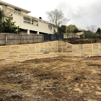 Multi-level timber sleeper retaining walls terracing a steep new-estate slope below existing townhouses
