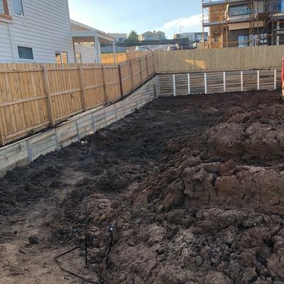 Timber sleeper retaining walls around a freshly cut backyard on a new build, with coastal homes behind