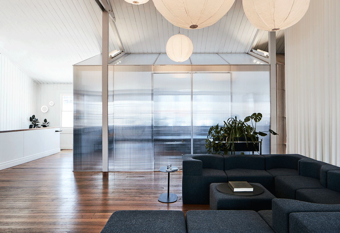 The Cloud workspace by Foolscap, the studio's Melbourne home base. The Foolscap-designed Souffle modular sofa sits in the foreground on dark timber floorboards. A polycarbonate-clad meeting room reflects the natural light around the room. Long white curtains hang from the 7m high ceilings.