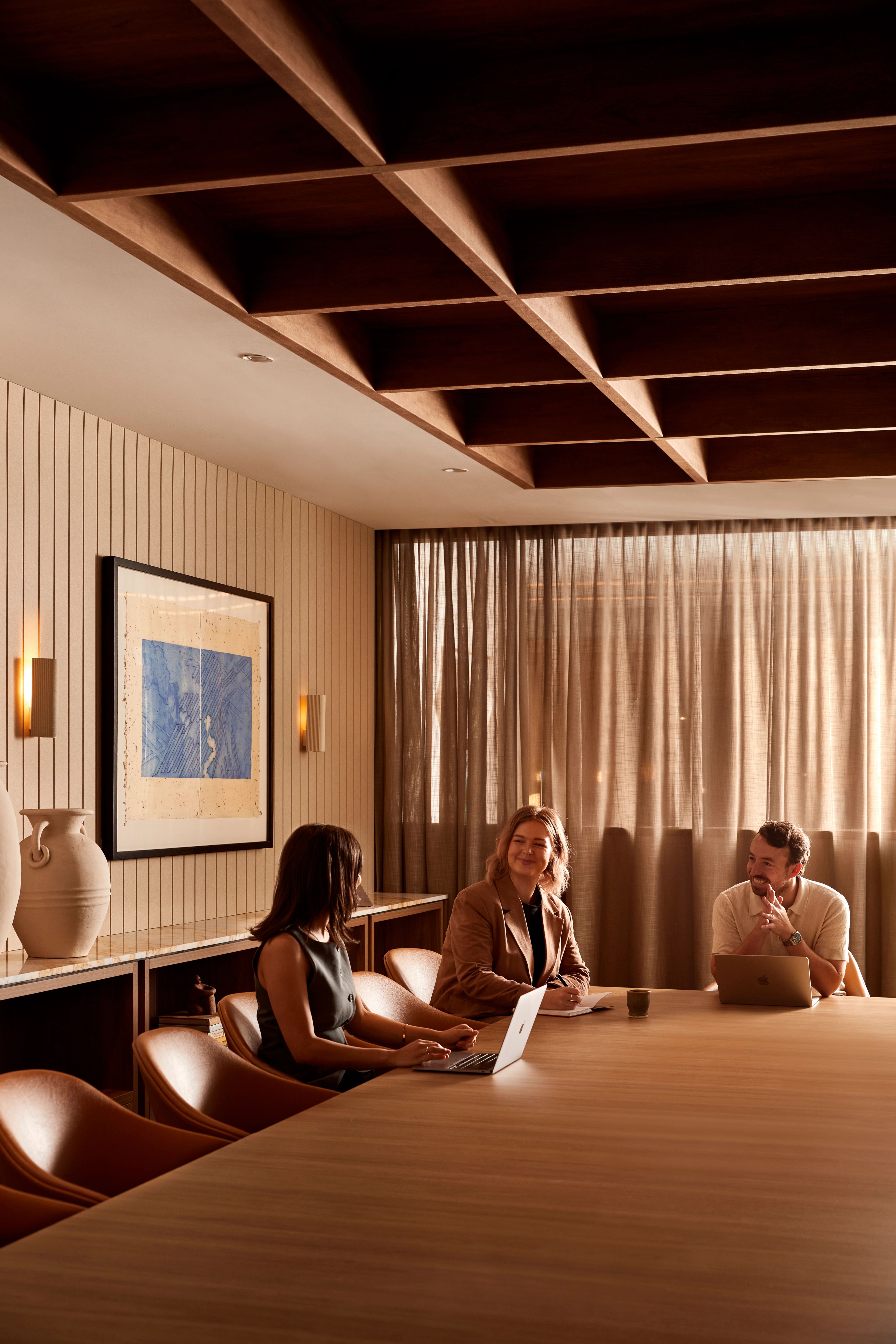 Three people having a meeting around a boardroom table at Forum Workspace, a co-working space designed by Foolscap. 