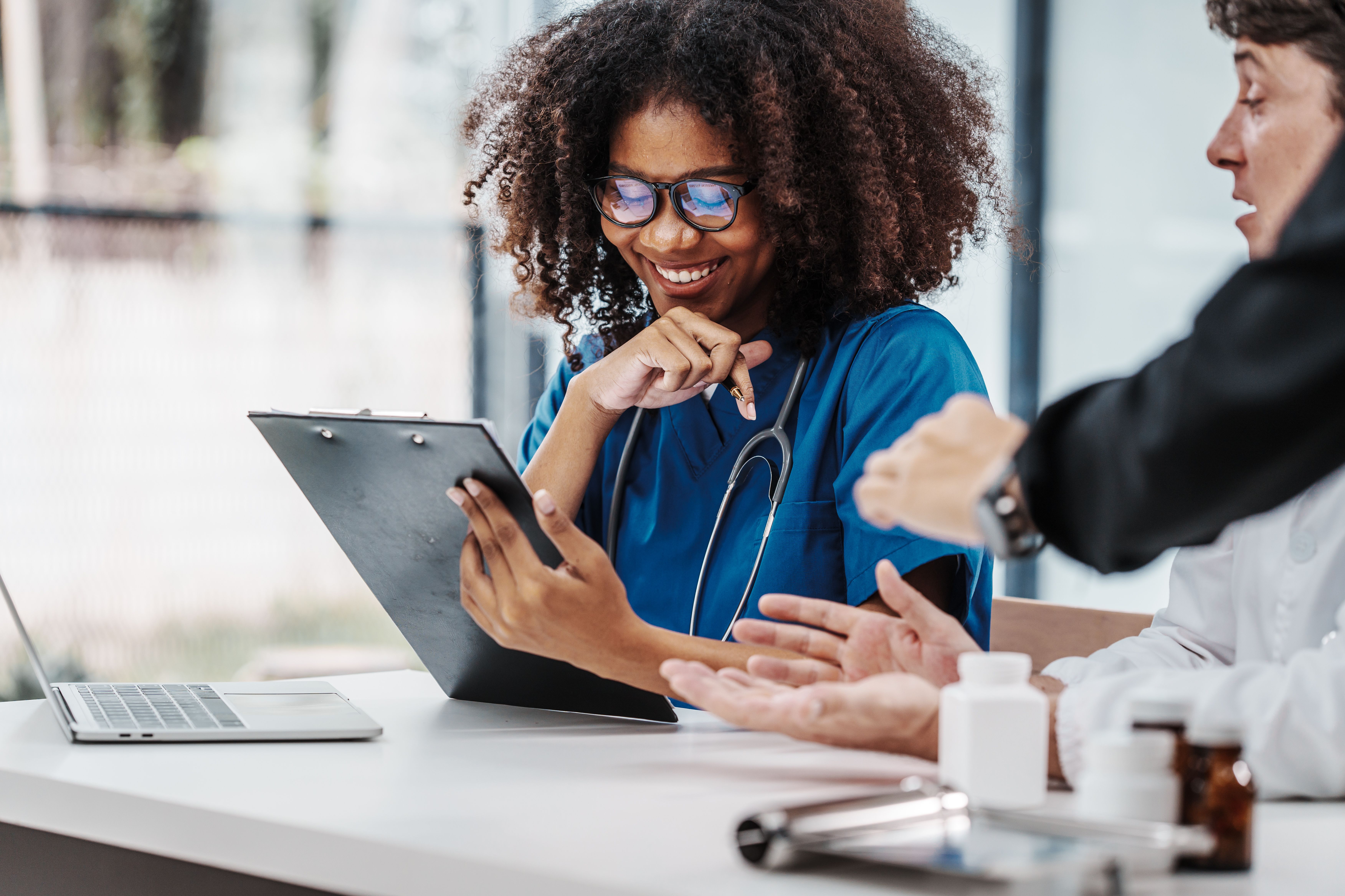 Hematologist writing a referral a ENJAYMO® infusion at violet health smiling with her patient.