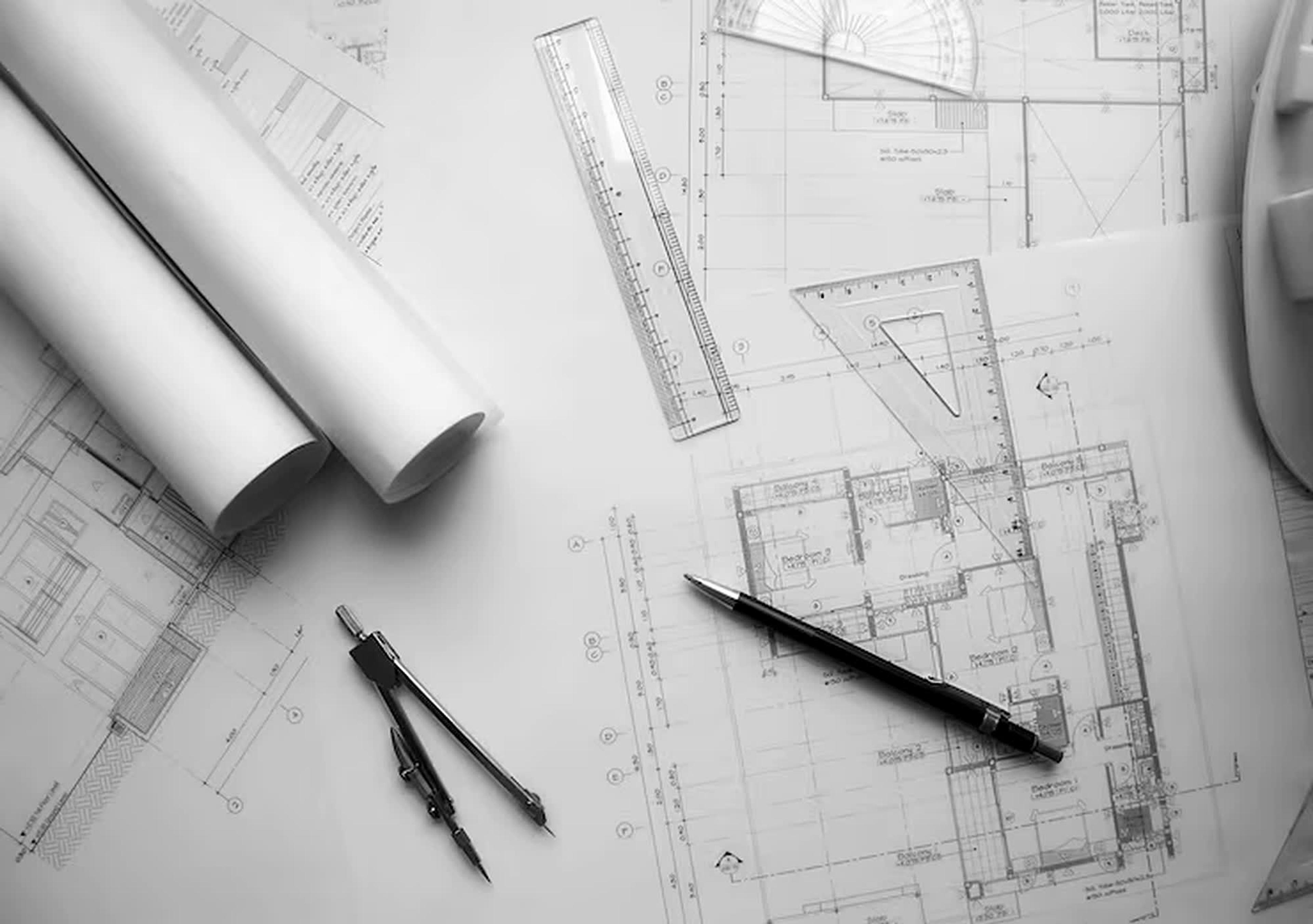 Planos de arquitectura con regla, escuadra y compás sobre una mesa de trabajo