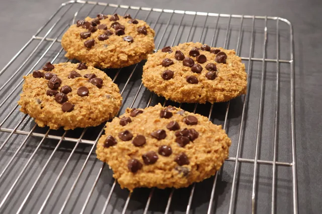 Four pumpkin chocolate chip cookies cooling on a wire rack