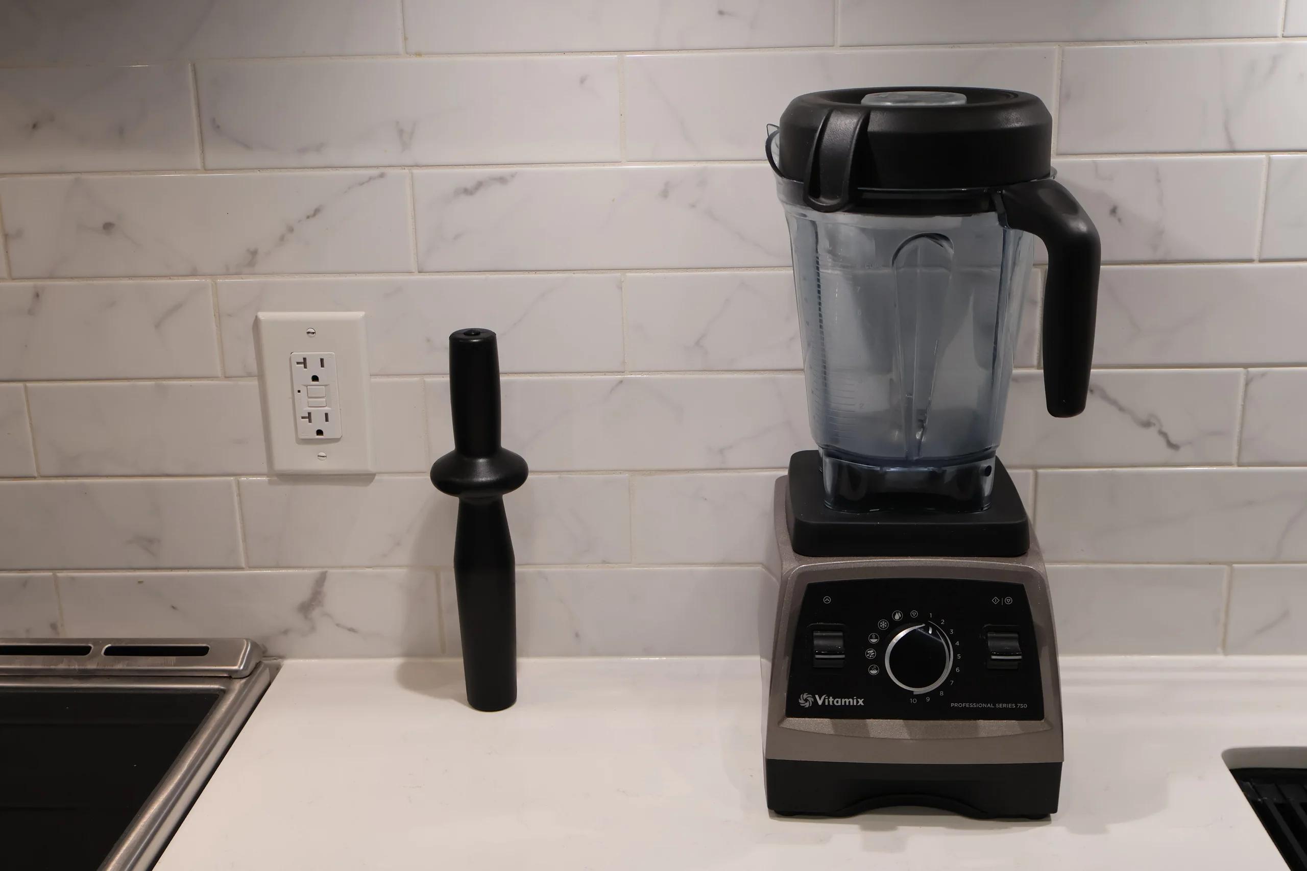 The Vitamix Pro 750 base and jug on the counter next to the tamper, seen from a little further back
