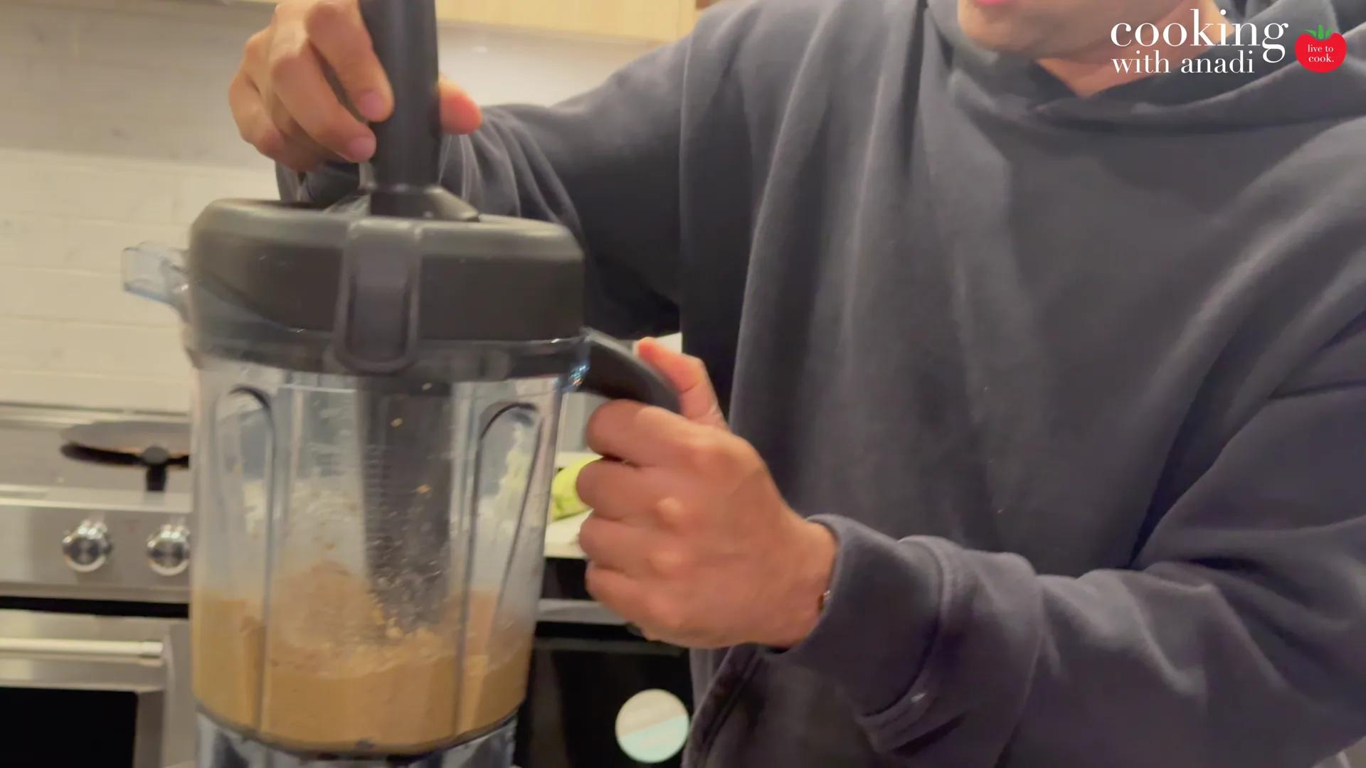 Anadi pressing the tamper down through the lid while the Vitamix runs
