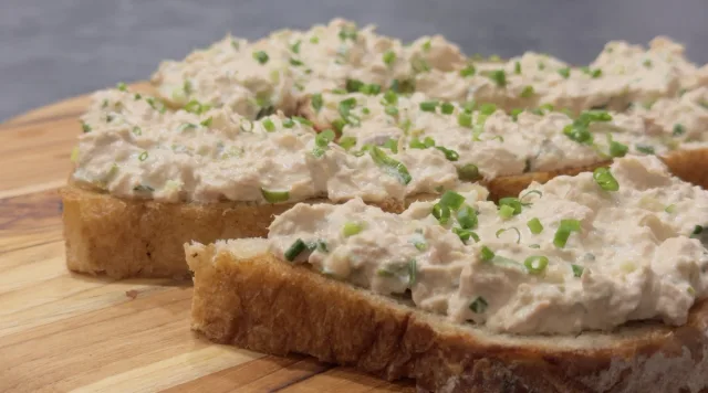 Tuna salad spread on toasted bread slices, garnished with chopped green onions.