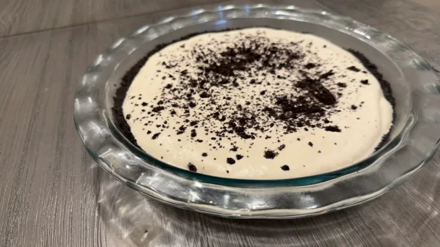 No-bake Oreo mud pie with creamy filling topped with crushed Oreo crumbs in a glass pie dish.