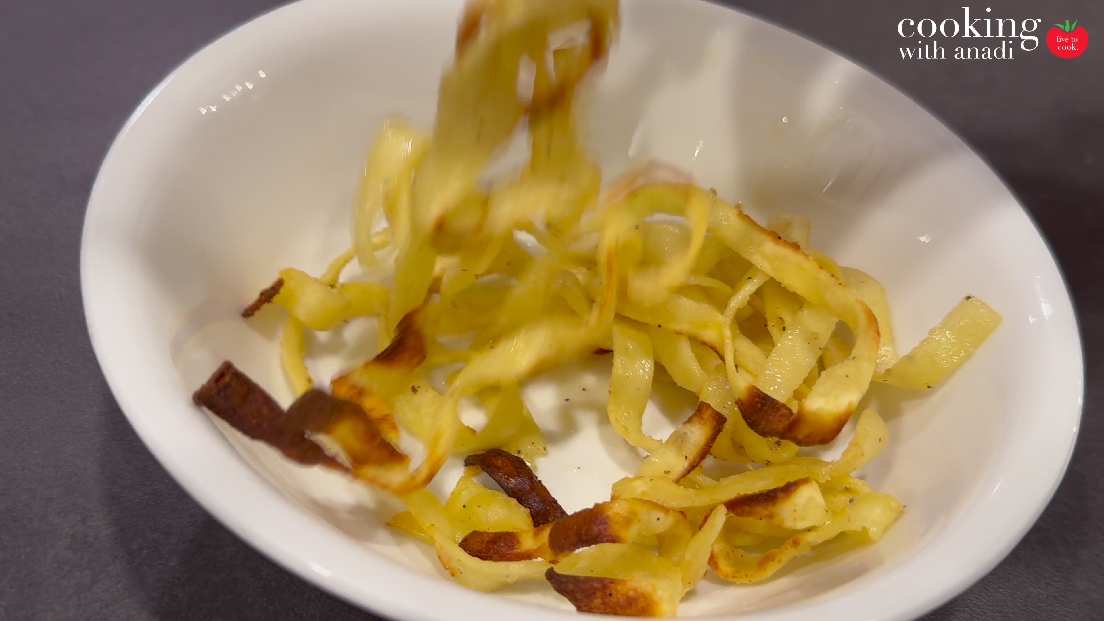 Leftover fettuccine alfredo after eight minutes in the air fryer, the strands browned and crisp in a white bowl