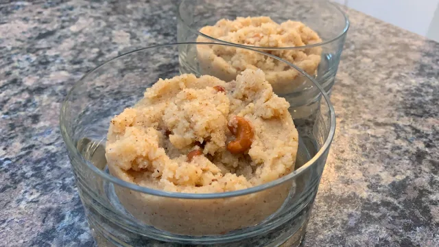 Two glass bowls of sooji halwa, a golden-brown semolina pudding with a crumbly, grainy texture topped with nuts.