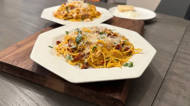 Golden crispy chow mein noodles topped with shredded cheese, bacon, and green onions on white plates.