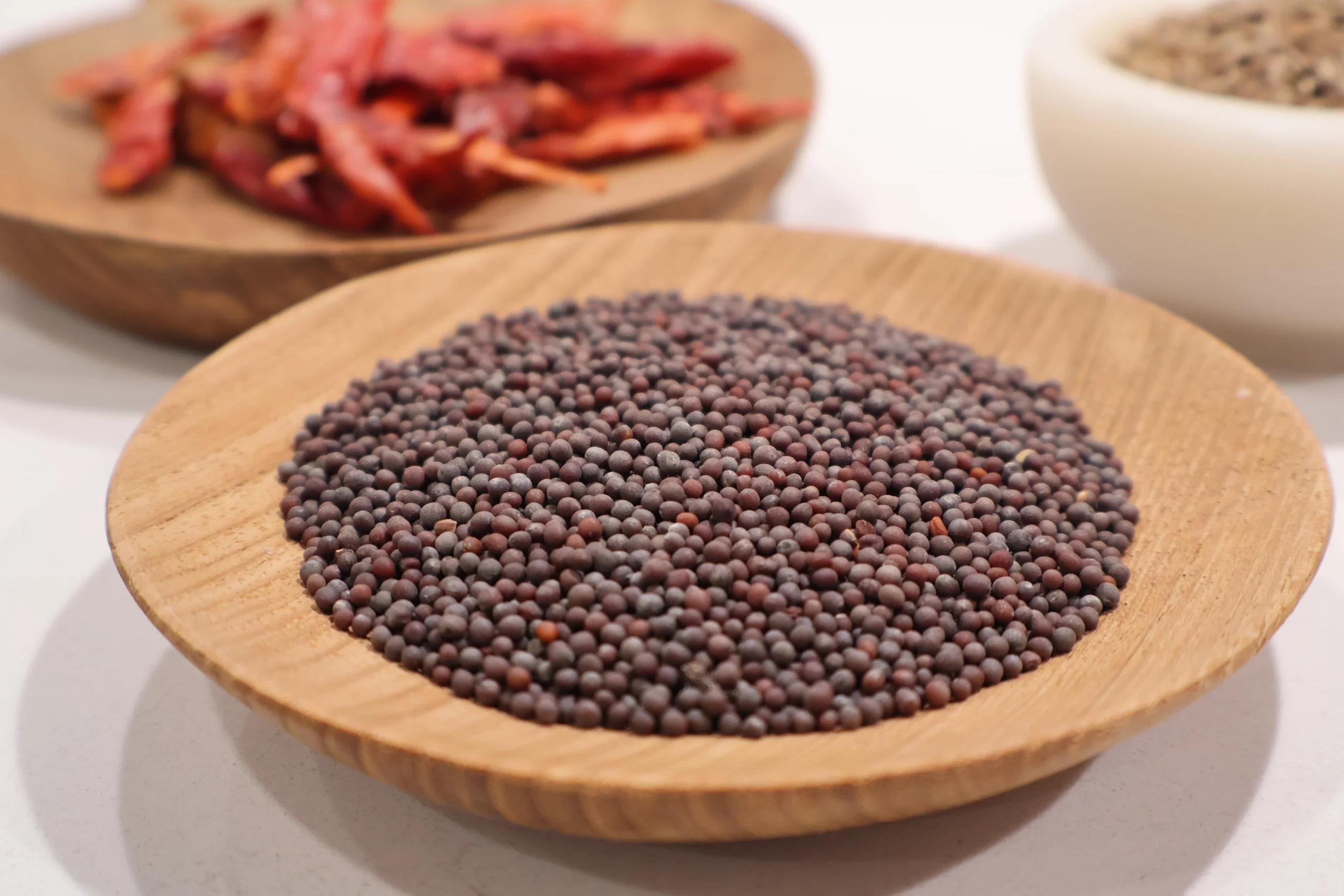 Whole brown mustard seeds in a wooden bowl, an ingredient for Indian tadka spice preparation.