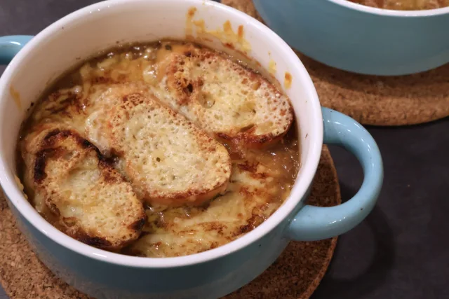 French onion soup in blue bowls topped with melted cheese and toasted bread slices.