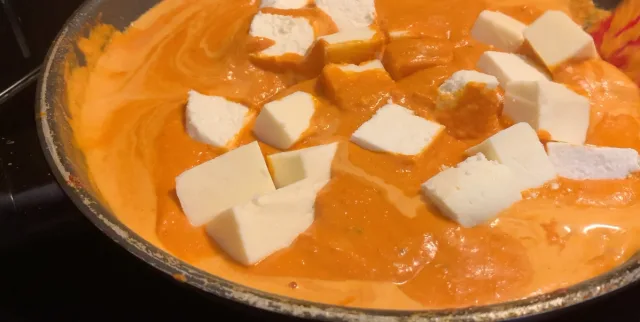 Shahi Paneer curry with white paneer cubes in creamy orange tomato sauce in a pan.